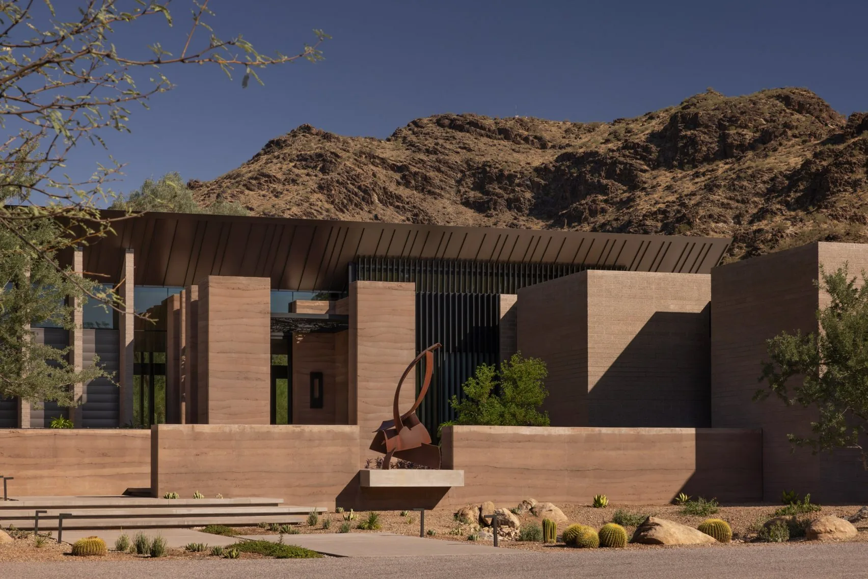 The house seen by day, low beneath the desert mountain.