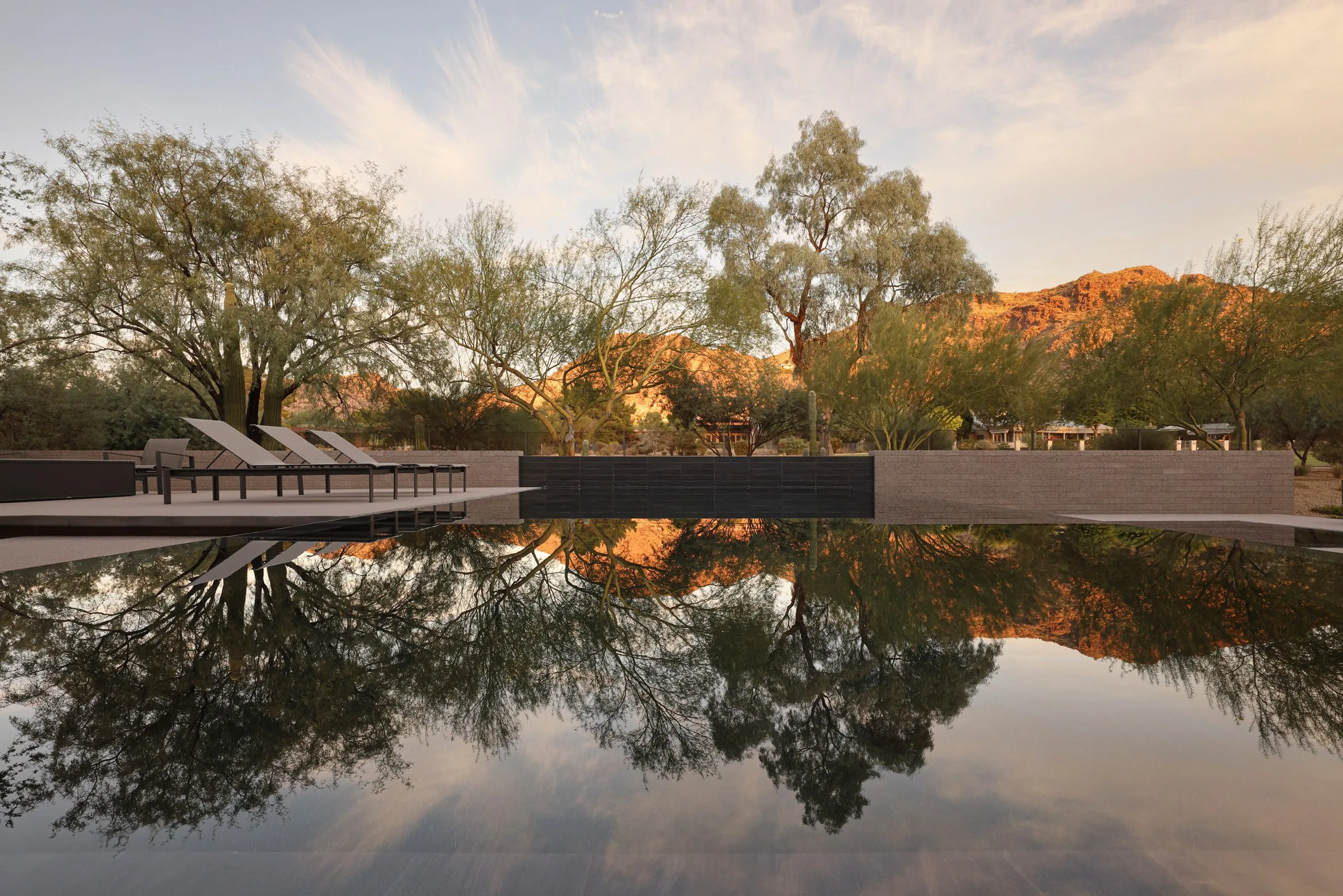 A reflecting pool mirroring the desert mountain glowing gold at sunset.