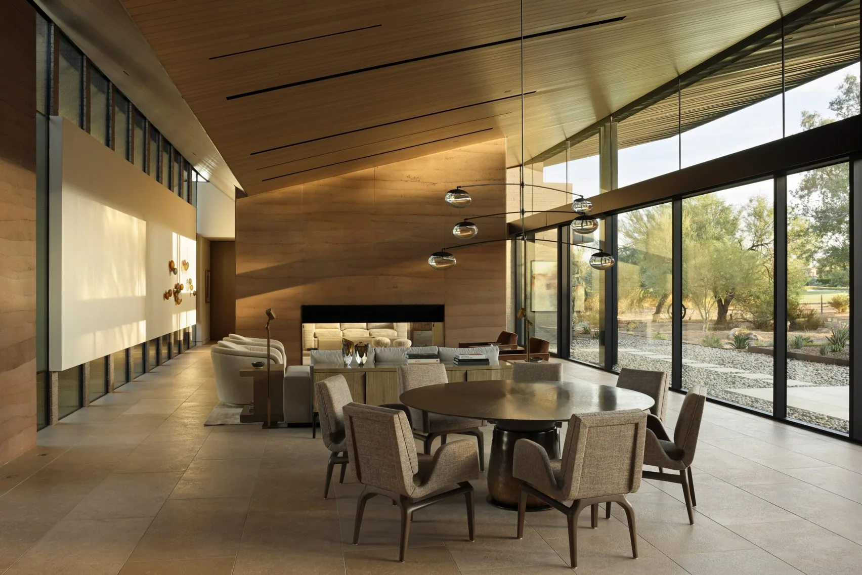 The living and dining space beneath a curved timber ceiling, opening to the desert.