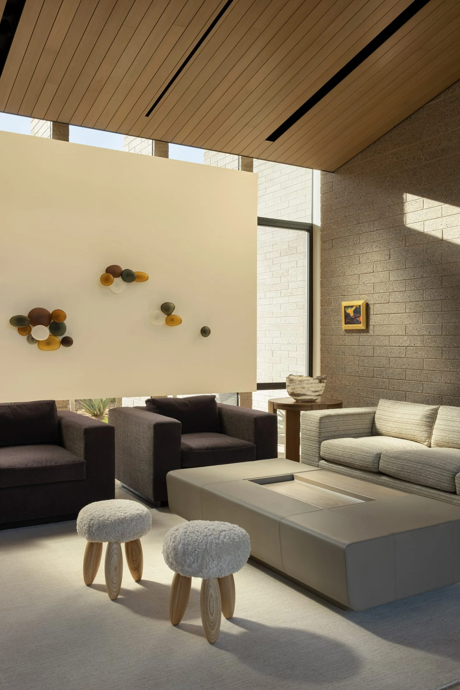 A double-height living room filled with golden light against a brick wall.