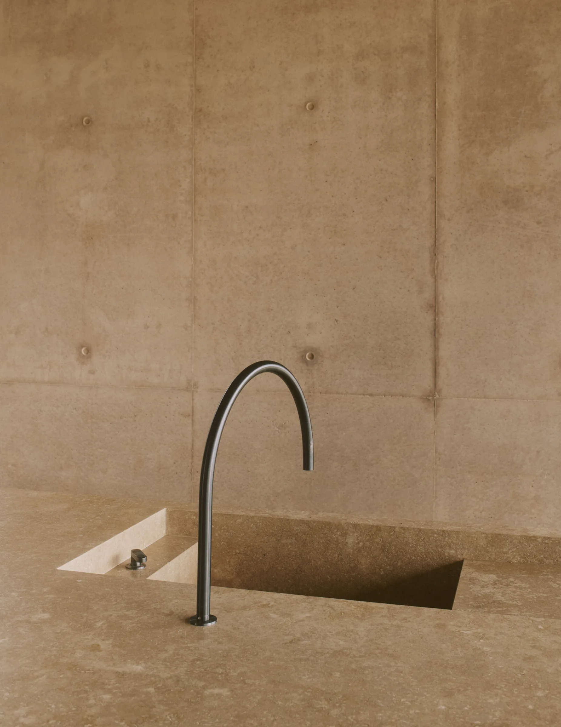 A slim tap rising from a concrete basin, a study in restraint.