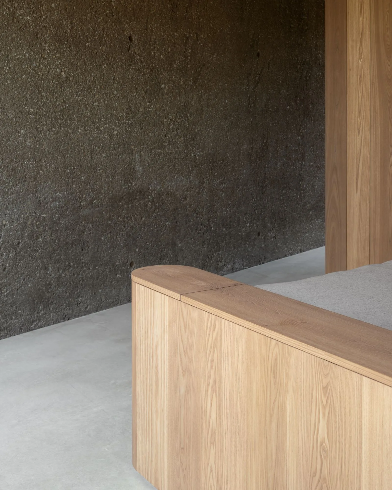 A close junction of oiled timber meeting board-marked concrete, detailed with care.