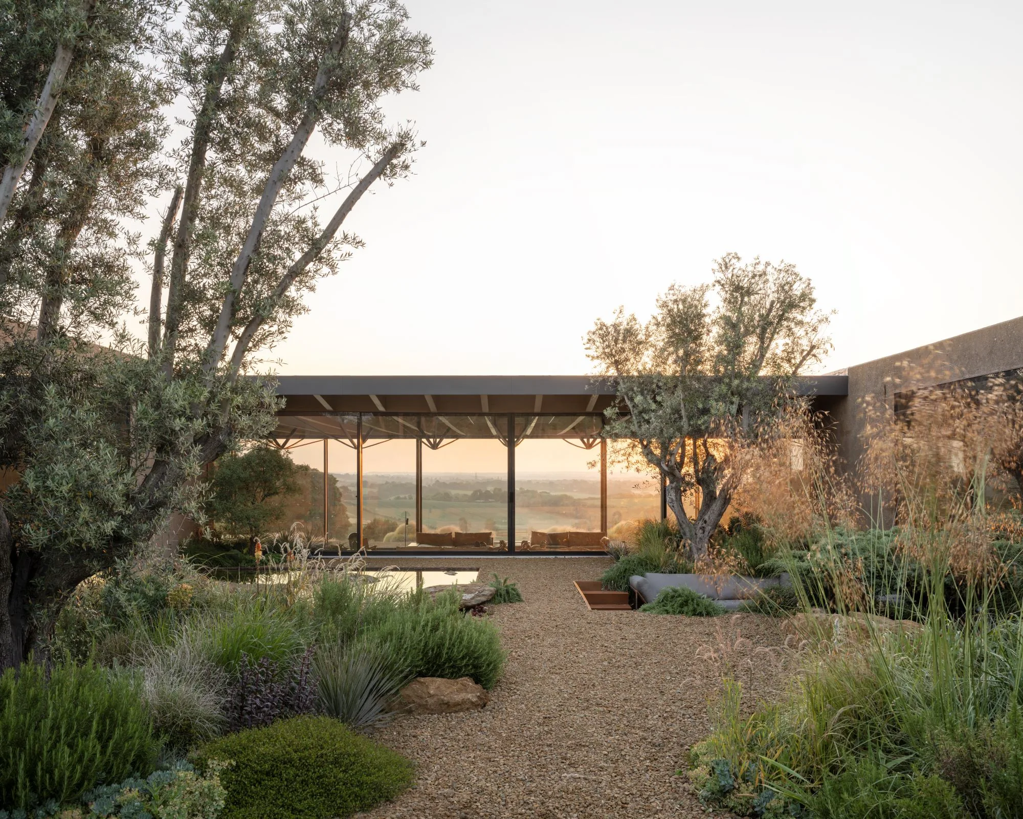 The garden at sunset, the pavilion glowing low behind planting.