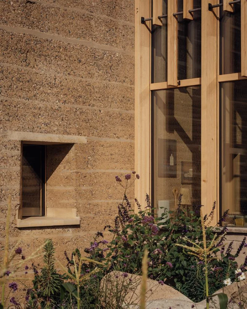 A close view of the rammed-earth wall, its horizontal strata and chalk aggregate visible.