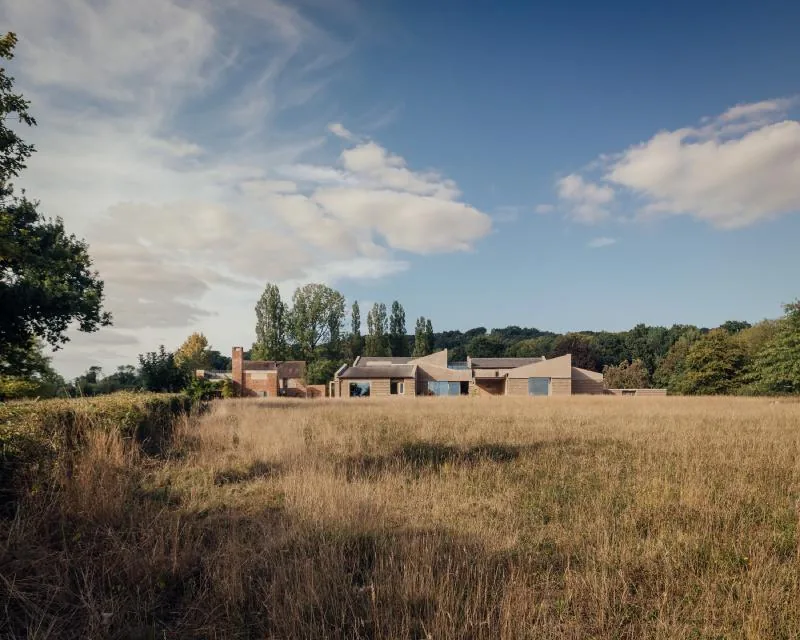 Marl House sitting low in a daytime Wiltshire meadow, beneath the tree line.