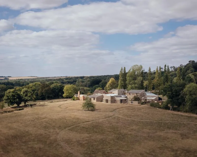 An aerial view of Marl House low in its valley, paths worn through the meadow.