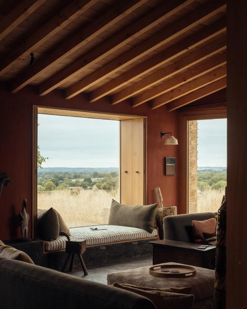 A deep terracotta room with a window seat framing the Wiltshire meadow.